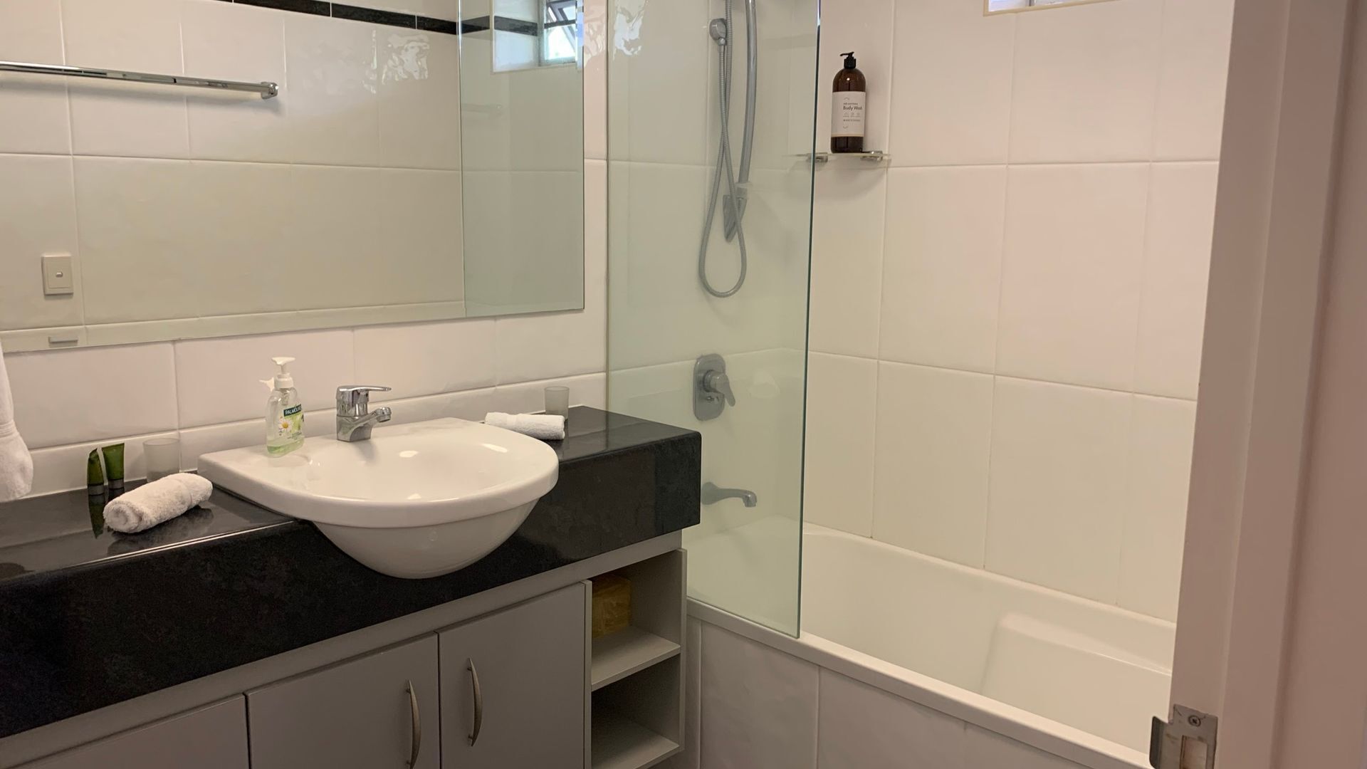 A bathroom with a white sink, a glass shower enclosure, and a mirror.