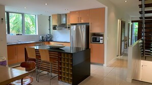 A modern kitchen with a central island, stainless steel appliances, and a view of the outdoors. - BHA 1 Beachfront Haven - 2 bedroom (Mission Beach)