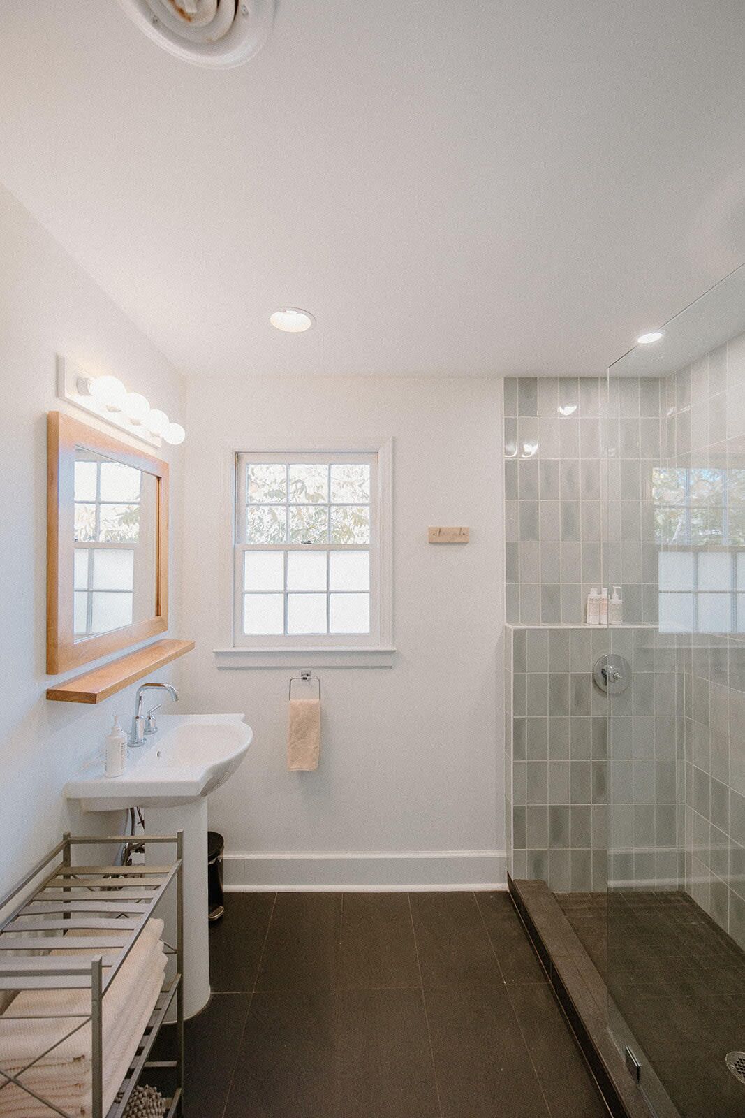 A modern bathroom with a white sink, vanity, and a glass shower enclosure.