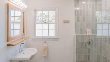 A modern bathroom with a white sink, vanity, and a glass shower enclosure.