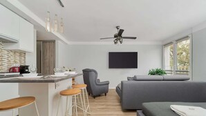 A modern kitchen with a bar area, a grey sofa, and a bed with a green blanket. - Stylish Studio in the Center | 15 minutes to the Market Square of Wroclaw (Wroclaw)