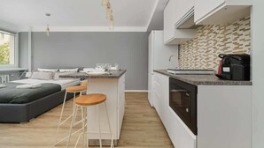 A modern kitchen with white cabinets, a built-in oven, and a coffee machine. - Stylish Studio in the Center | 15 minutes to the Market Square of Wroclaw (Wroclaw)