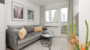 A modern living room with a grey sofa, a small round table, and two framed pictures on the wall.