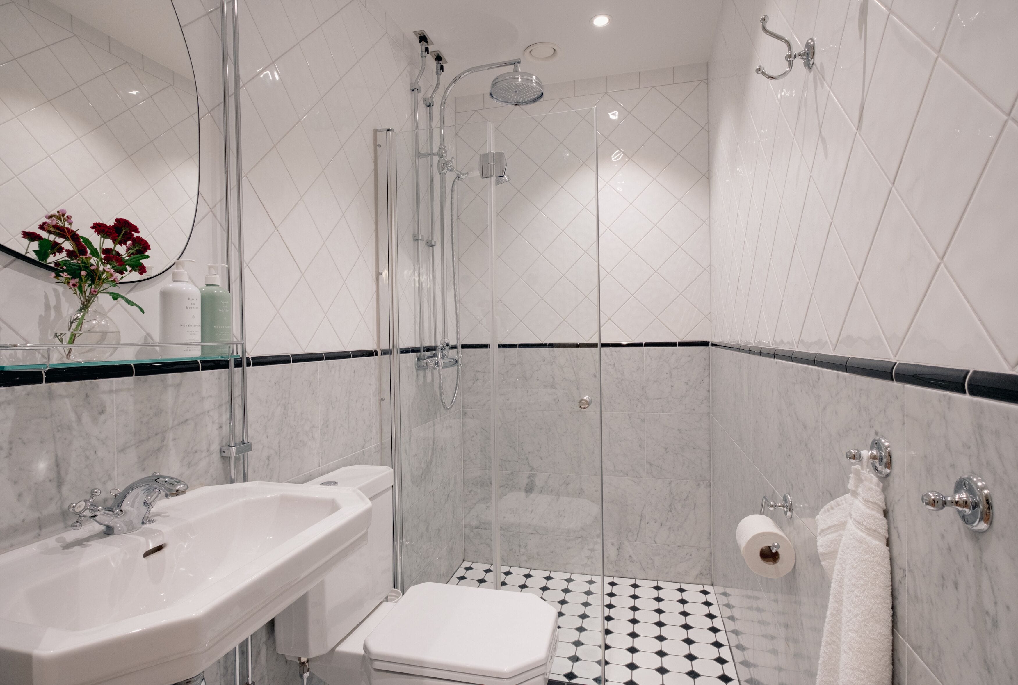 A modern bathroom with a glass-enclosed shower, a white sink, and a toilet.