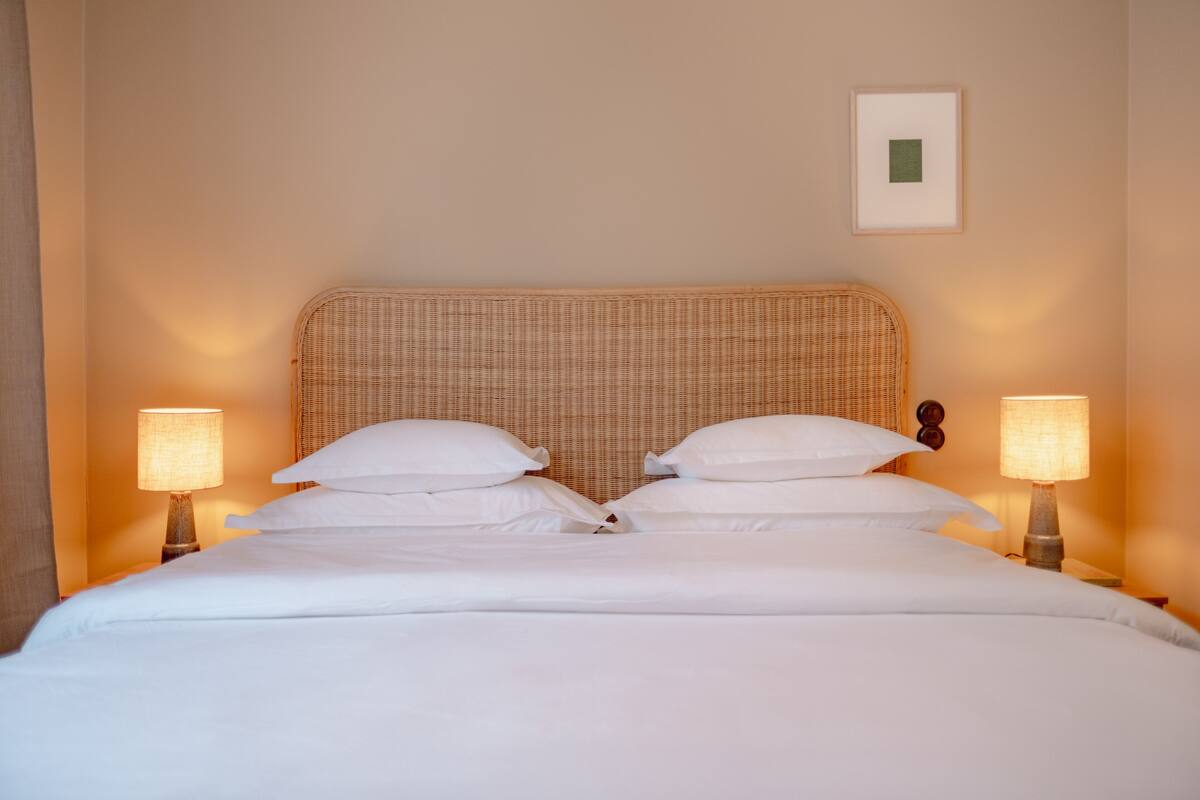 A neatly made bed with white linens and two bedside lamps.