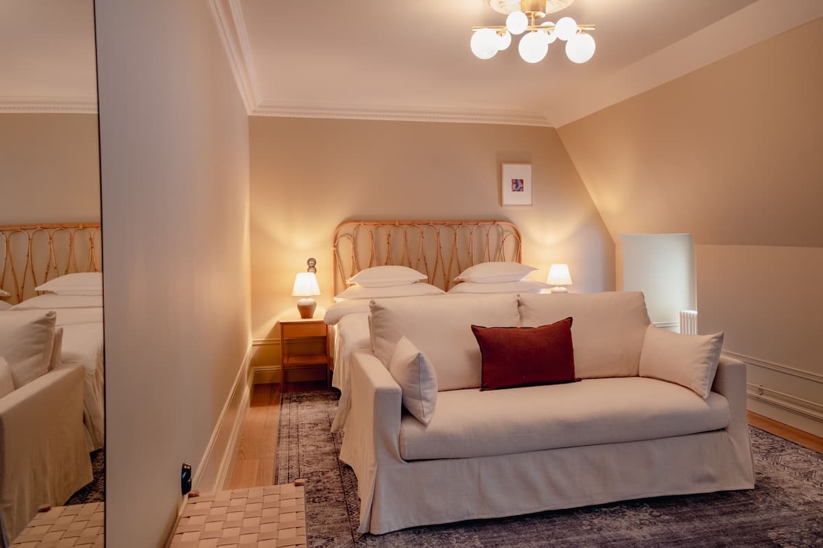 A hotel room with a bed, a sofa, a nightstand with lamps, and a ceiling light fixture.