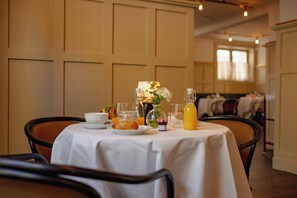 A dining table set with breakfast items, including a glass of orange juice, a bottle of milk, and a plate of food. - Clas på Hörnet (Stockholm)