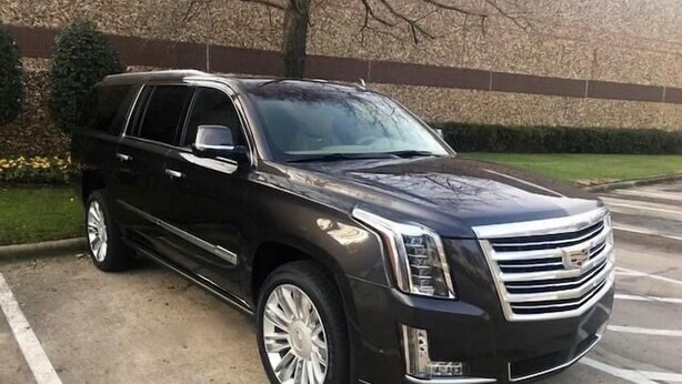 A black Cadillac SUV parked in a lot with a building in the background. - Single Story 3BR w/ Pool, Hot Tub, Firepit & Grill (Henderson)