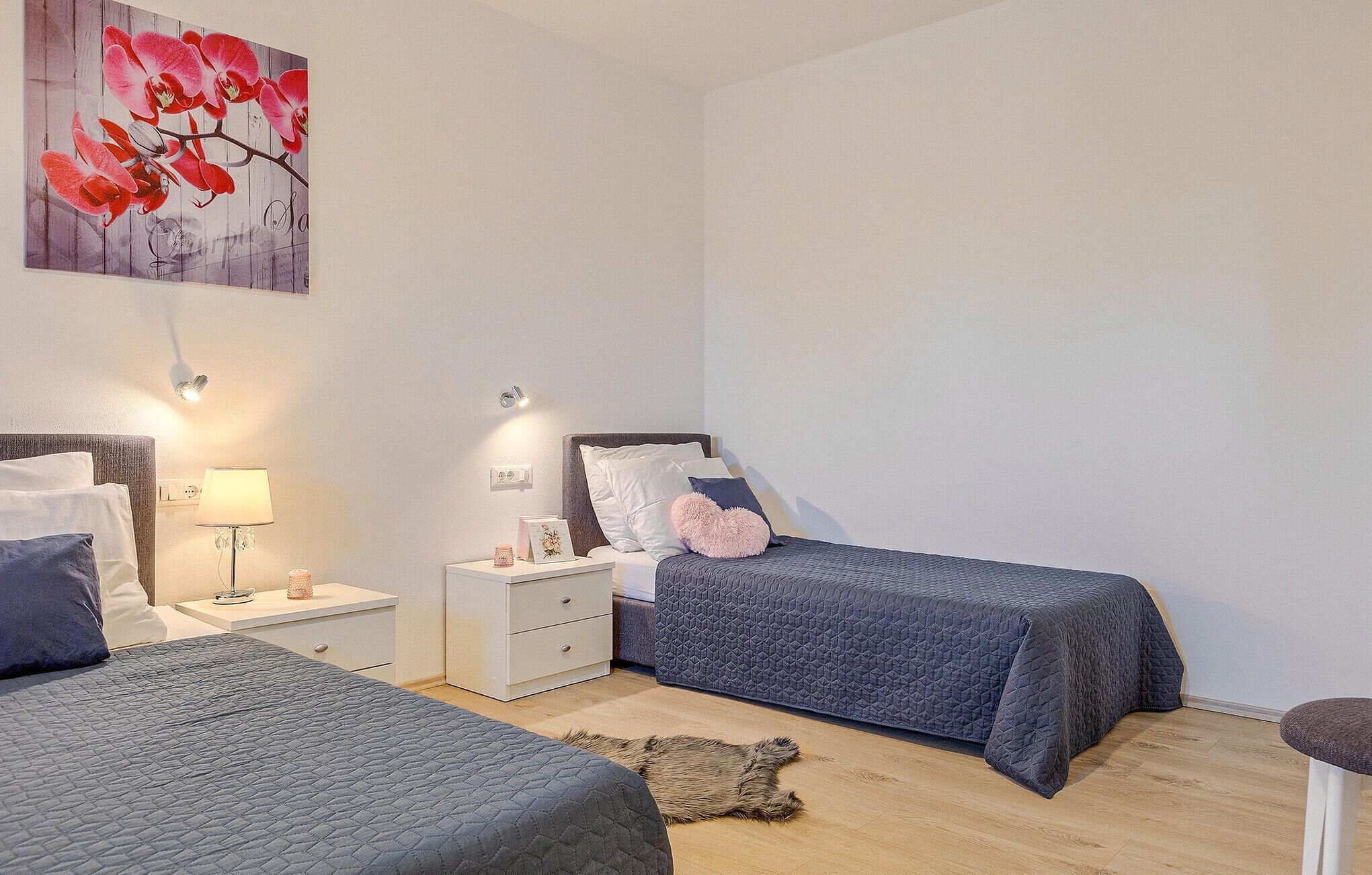 Une chambre avec deux lits, une table de chevet, une lampe et un tableau au mur.