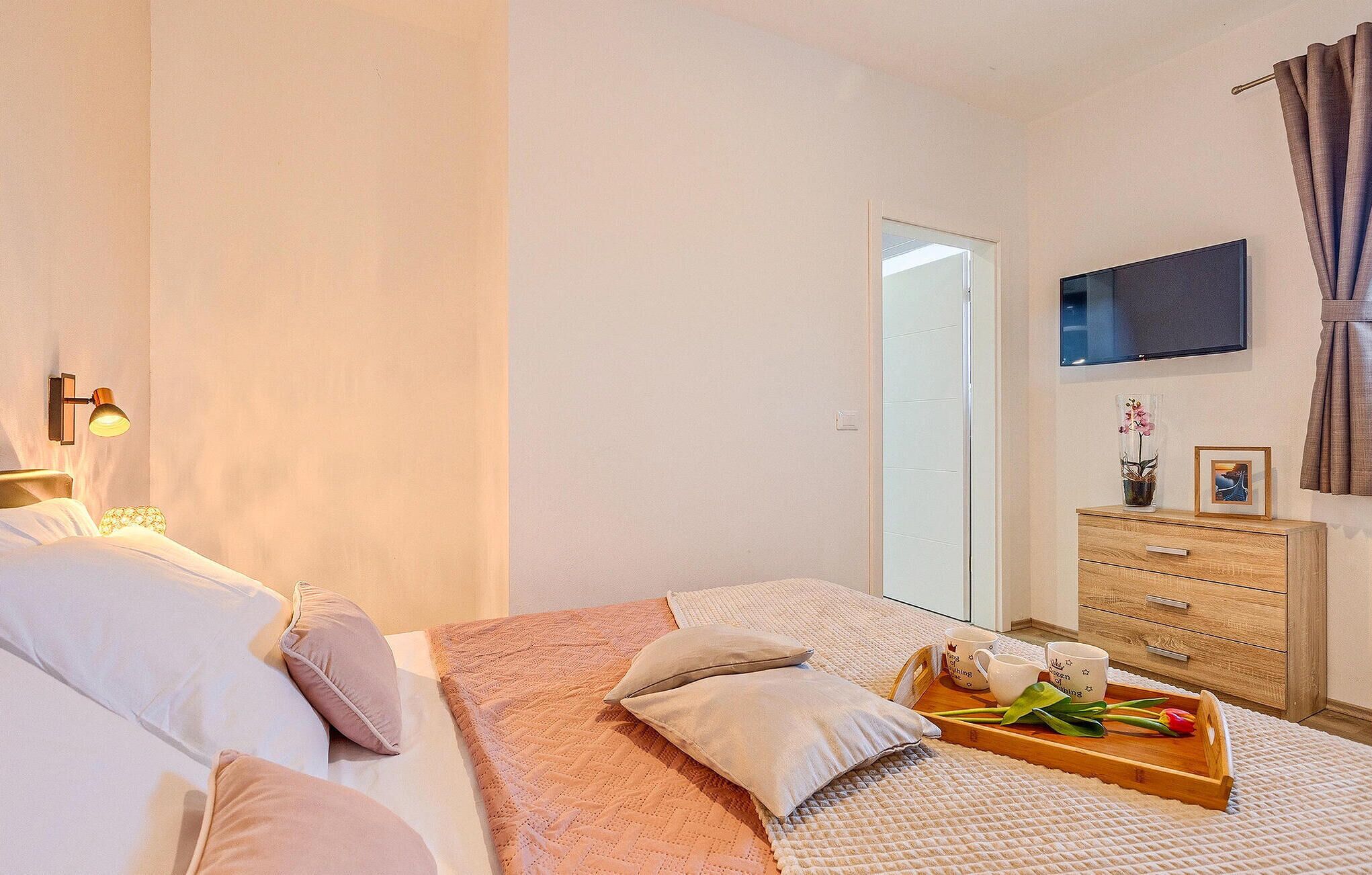 Un dormitorio con cama, mesita de noche, televisor y cómoda de madera.