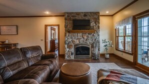 Una sala de estar con chimenea de piedra, sofás de cuero y un ventanal grande.