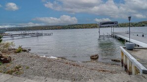 Muelle frente al agua con un área de descanso cubierta y un farol.