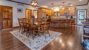Una cocina amplia con armarios de madera, una isla central y un comedor con una mesa grande de madera y sillas.