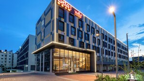 Un hotel moderno con fachada de vidrio, un letrero llamativo y una entrada bien iluminada.