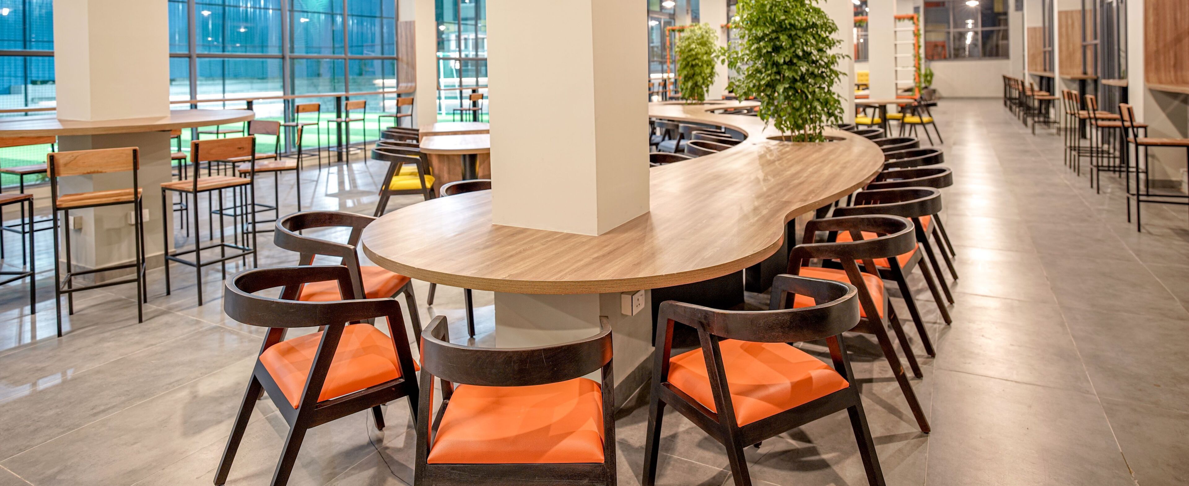 Un comedor moderno con una mesa redonda rodeada de sillas de madera con cojines naranja.