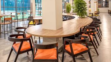 Un comedor moderno con una mesa redonda rodeada de sillas de madera con cojines naranja.