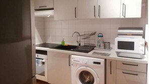 Ett kompakt kök med diskho, mikrovågsugn och tvättmaskin.