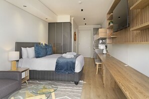 A modern bedroom with a bed, bedside tables, a TV mounted on the wall, and a wooden desk. - Ellipse Waterfall 31015 (Midrand)