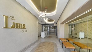 Un interior moderno con un mostrador de recepción, bancos y un cartel que dice "The Luna Club".