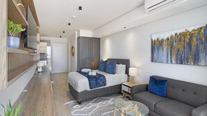 A modern hotel room with a bed, a sofa, a glass coffee table, and a painting on the wall. - Ellipse Waterfall 31002 (Midrand)