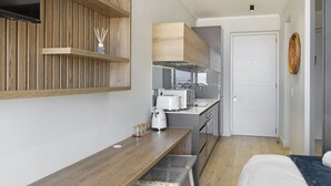 Una habitación pequeña con un banco de madera, una mesita y una cama.