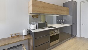 A modern kitchen with a microwave, toaster, and kettle on the counter, a sink, and a wooden cabinet above. - Ellipse Waterfall 31002 (Midrand)