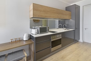 A modern kitchen with a microwave, toaster, and kettle on the counter, a sink, and a wooden cabinet above. - Ellipse Waterfall 31002 (Midrand)