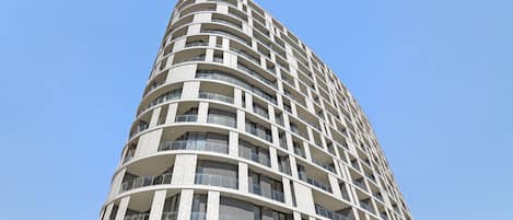 Un edificio moderno de gran altura con fachada curva, varios balcones y amplias ventanas.