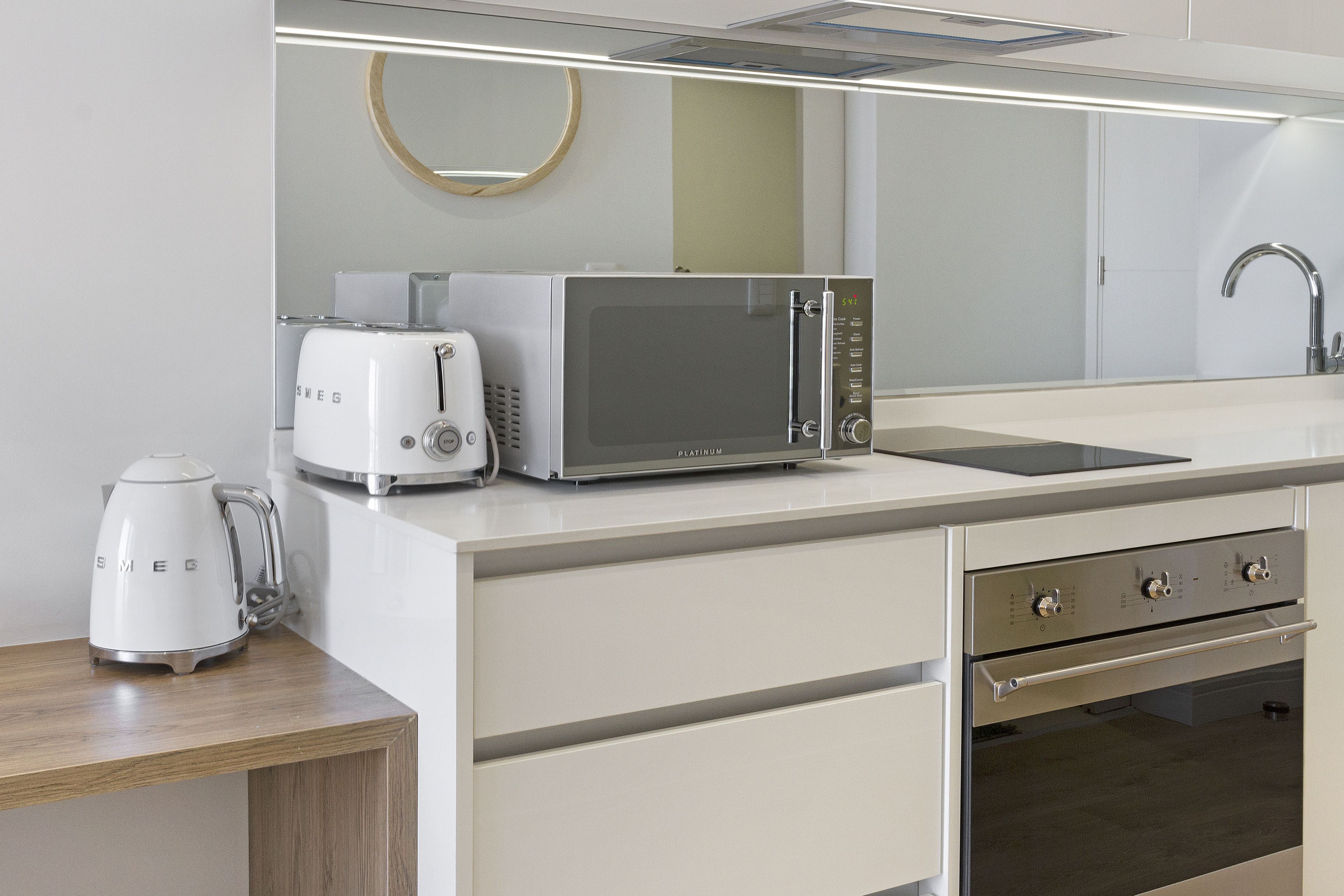 A modern kitchen with a microwave, toaster, and coffee maker on the counter, a sink, and a stainless steel oven.