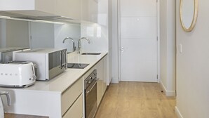 Una cocina moderna con electrodomésticos blancos, un lavamanos doble y suelo de madera.
