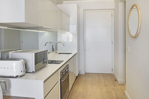 A modern kitchen with white appliances, a double sink, and a wooden floor. - Ellipse Waterfall 3902 (Midrand)