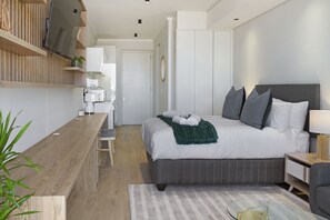 A modern bedroom with a large bed, bedside tables, a flat-screen TV, and a wooden desk. - Ellipse Waterfall 3902 (Midrand)