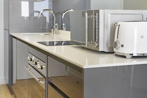 A modern kitchen with a stainless steel range hood, a white toaster, and a double sink.