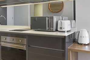Een moderne keuken met een RVS magnetron, broodrooster en koffiezetapparaat op het aanrecht.