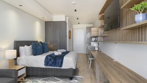 Une chambre d’hôtel moderne équipée d’un lit, d’une table de chevet, d’une lampe et d’un téléviseur fixé au mur.