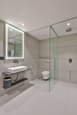 A modern bathroom with a glass-enclosed shower, a white sink, and a toilet.