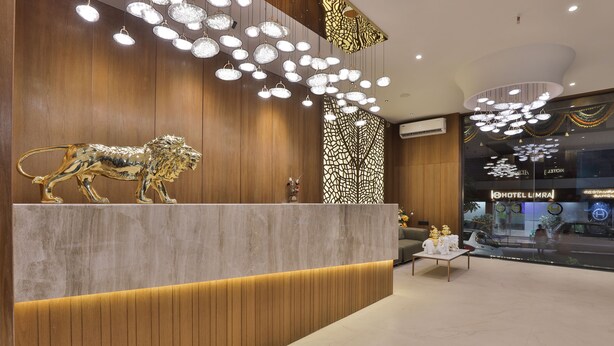 Uma área de recepção de hotel com um balcão de madeira, uma escultura de leão e luminárias modernas.