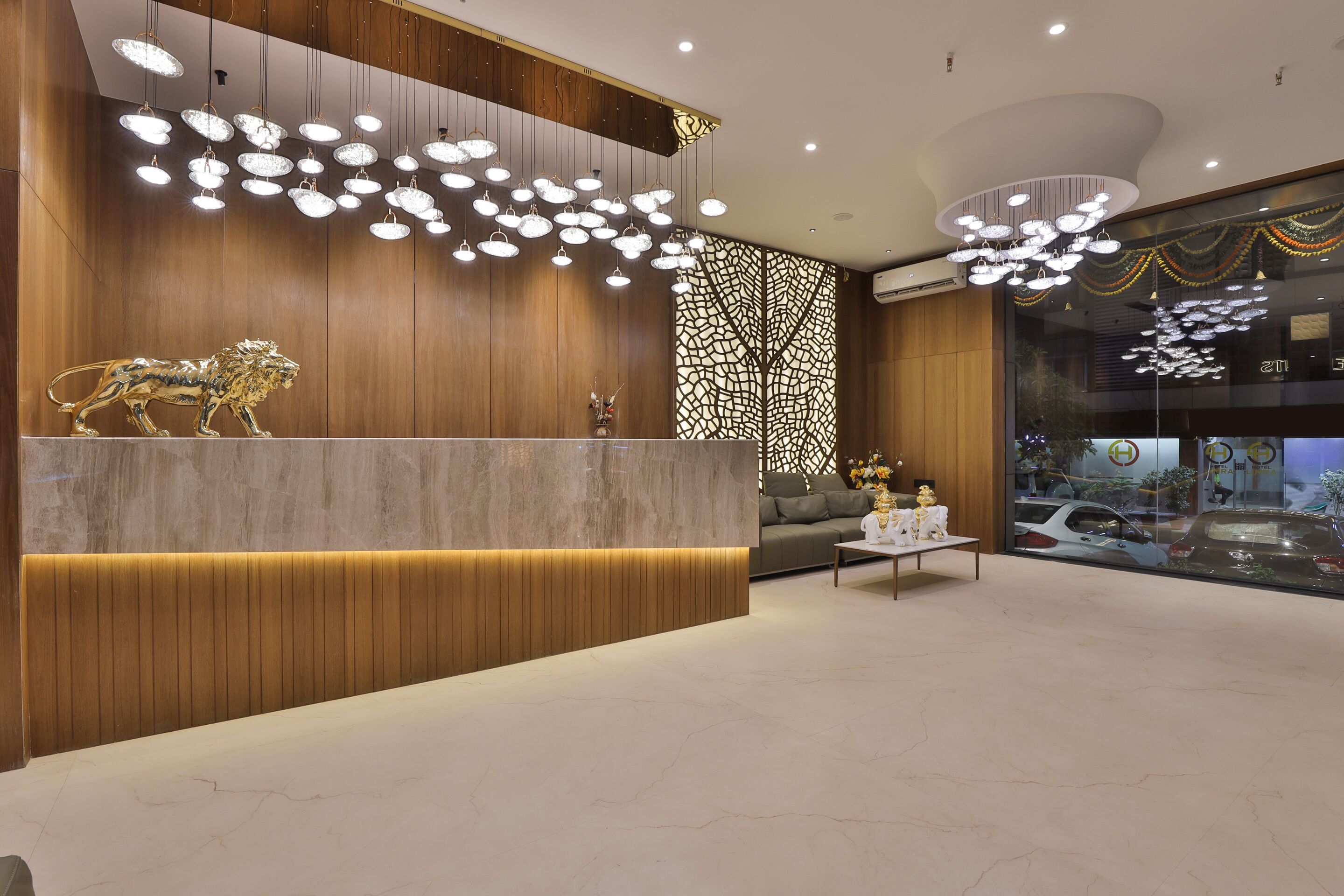 A modern reception area with a marble counter, a decorative lion sculpture, and a patterned wall.