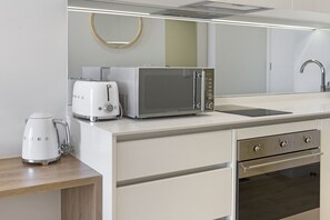 A modern kitchen with a microwave, toaster, and coffee maker on the counter, a sink, and a stainless steel oven. - Ellipse Waterfall 3802 (Midrand)