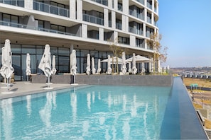 Un hôtel moderne doté d’une piscine, de parasols et offrant une vue sur la ville.