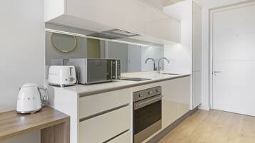 A modern kitchen with a microwave, toaster, kettle, and oven.