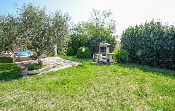 A backyard with a barbecue grill, a swimming pool, and a garden area.