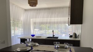Une cuisine moderne dotée d’un grand îlot central, d’un évier et donnant sur un jardin.