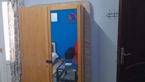 Une pièce avec une porte en bois, un mur bleu, une horloge et une petite table sur laquelle se trouve une télécommande.