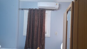 Une pièce avec une fenêtre, un climatiseur et un rideau.