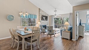 A dining area with a wooden table and chairs, a chandelier, and a stone accent wall.