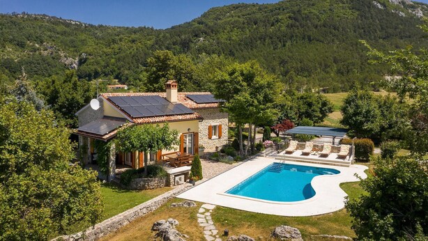 Ein Haus mit Schwimmbad, umgeben von einem Garten und einer Berglandschaft.