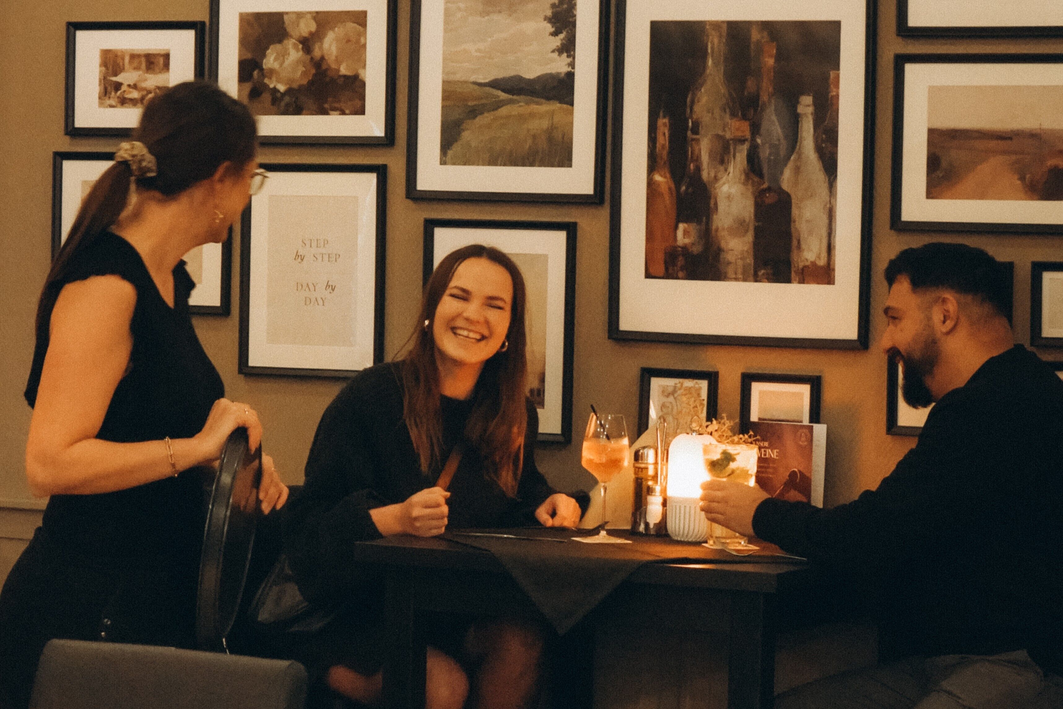 A dining area with framed artwork on the walls, a table with a candle, and a menu.
