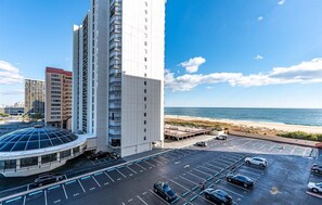 Een hoog hotel met een parkeerplaats en uitzicht op het strand.