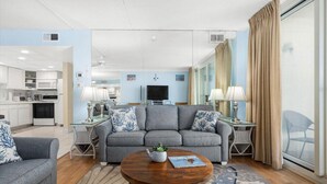 A modern living room with a grey sofa, two side tables, a coffee table, and a TV.